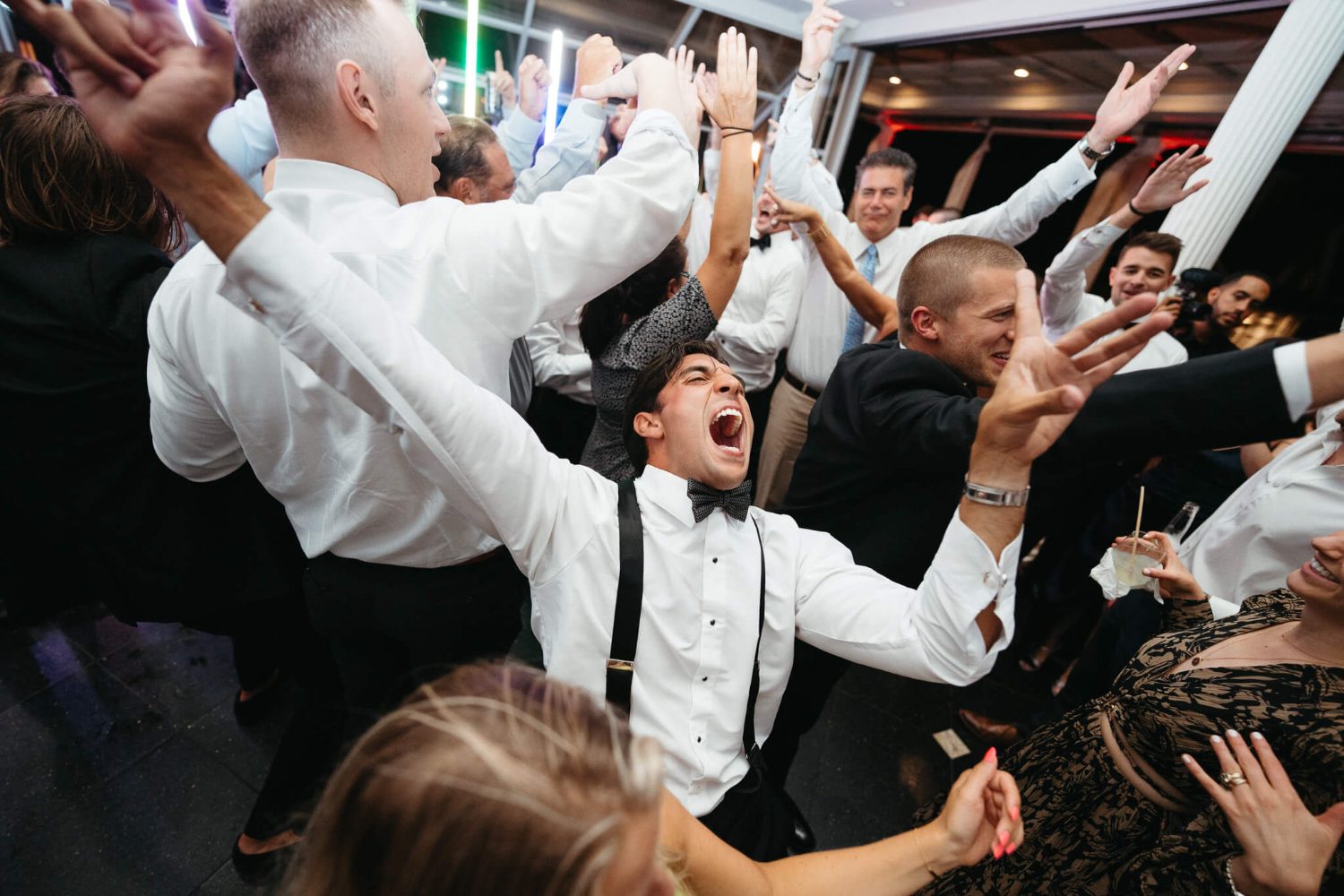Groomsmen shouting with arms raised on a packed floor