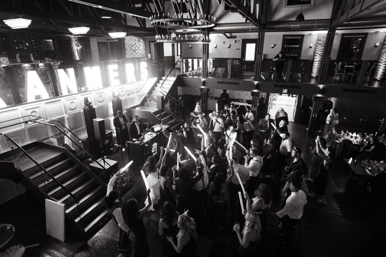 Black and white view of a packed reception with glow sticks